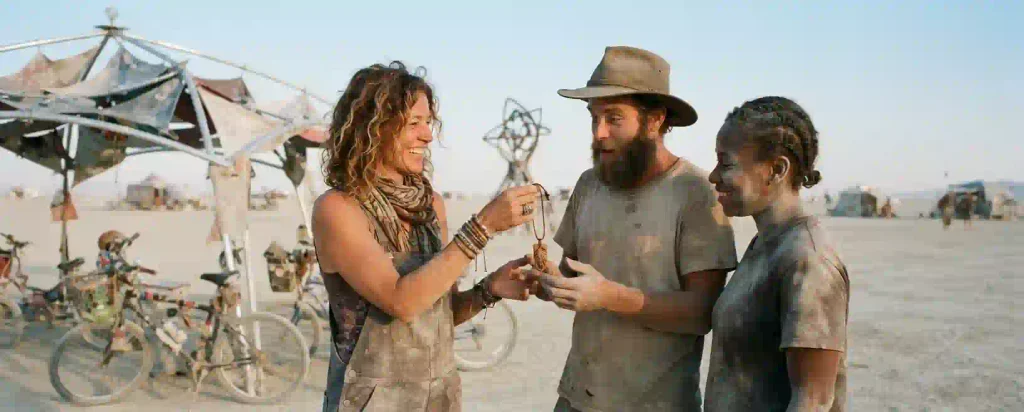 Burning Man participants sharing a handmade gift at a desert camp